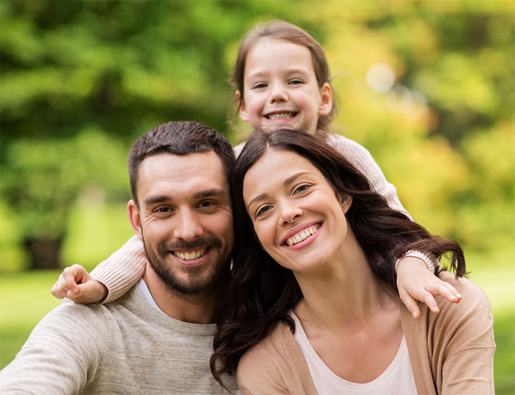 Family of three smiling in nature